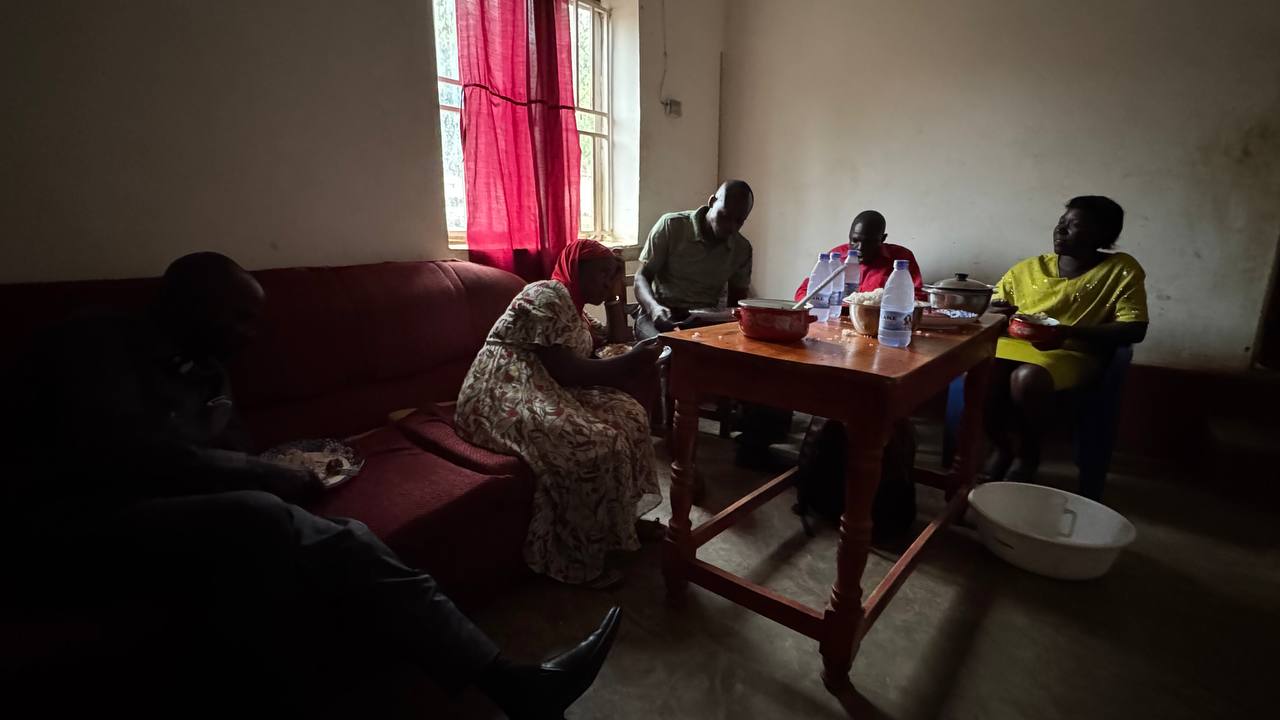People sharing a meal indoors after the Kagadi Prison visit.