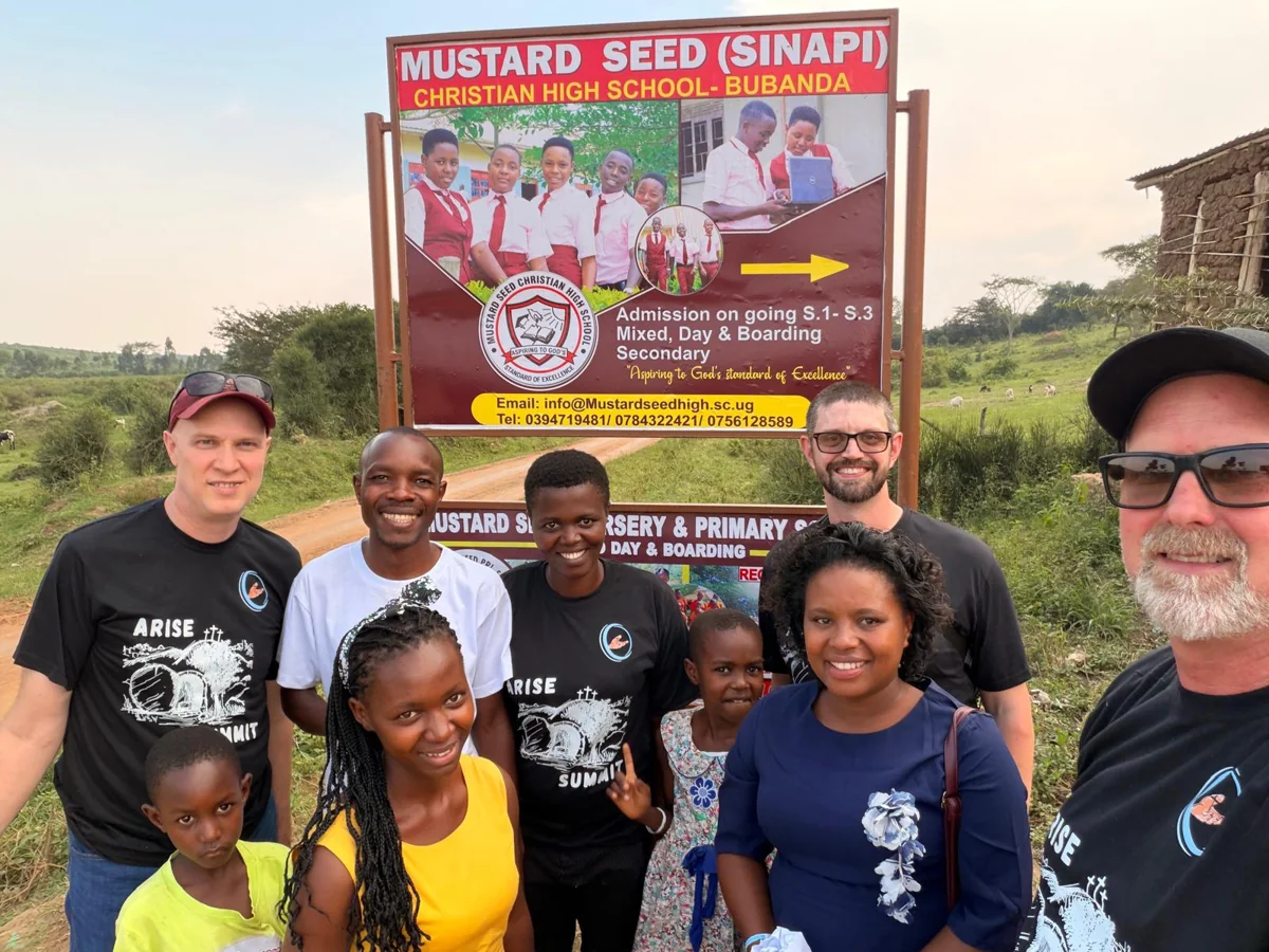 Visitors and local friends gathered beneath the Mustard Seed school sign.